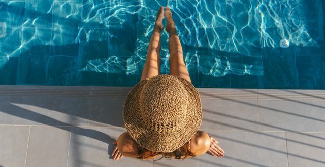 Persona protegiendo la piel y el cabello durante el verano mediante una correcta hidratación y alimentación.